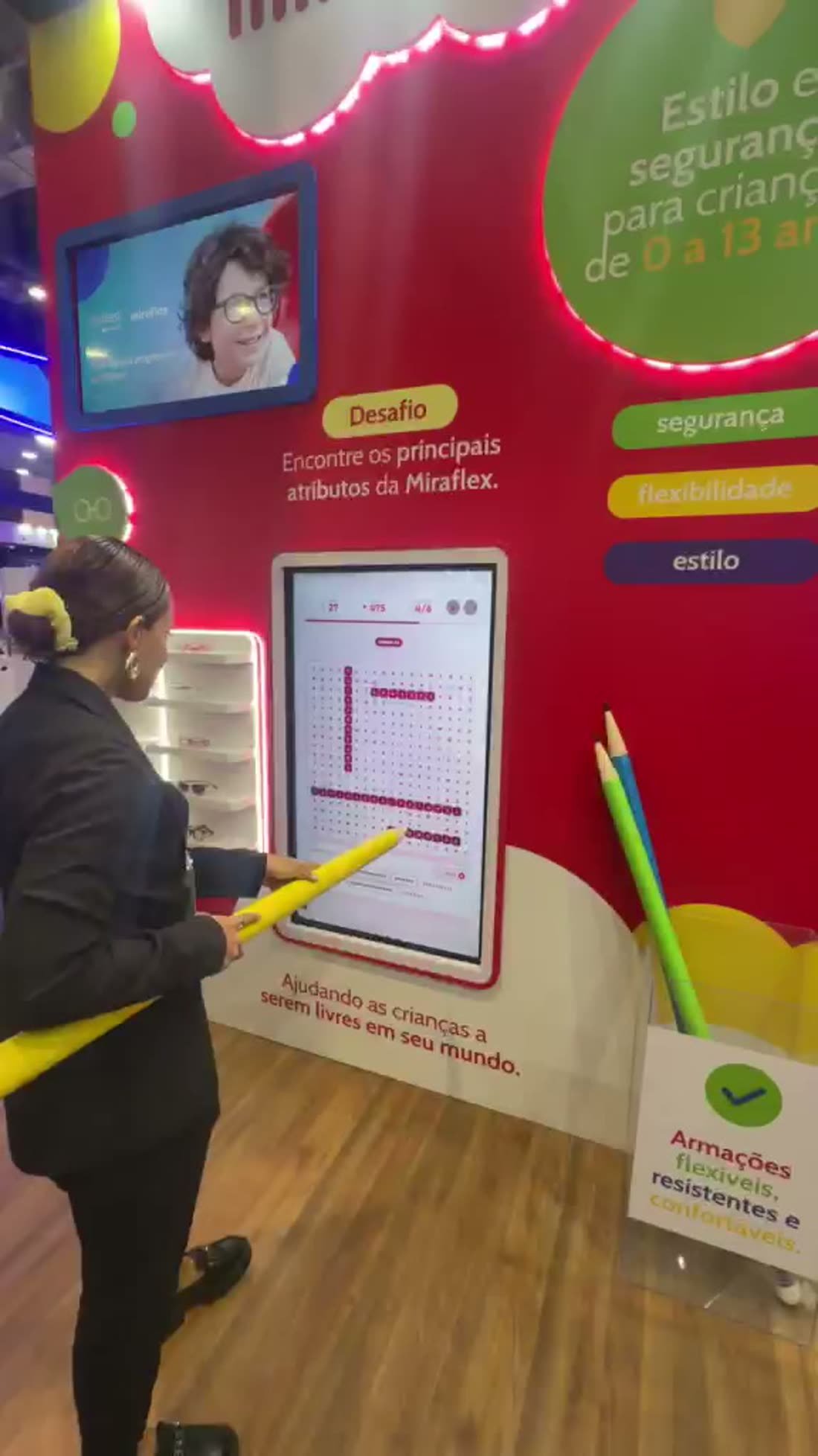 Participante marcando as palavras na tela touch com um lápis cenográfico gigante durante a partida