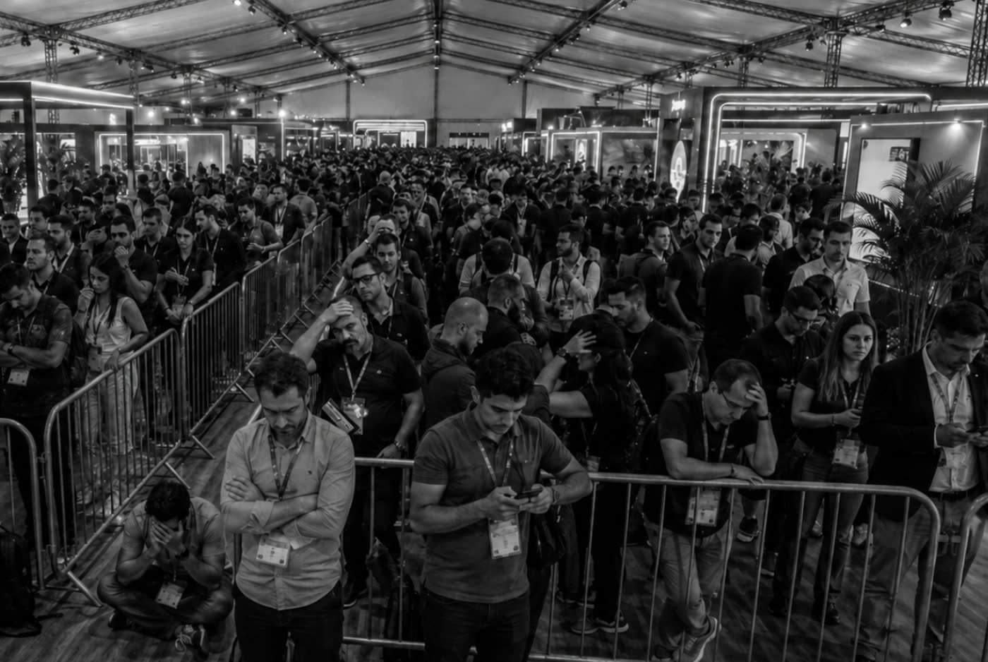 Público parado em fila física com grades em um evento