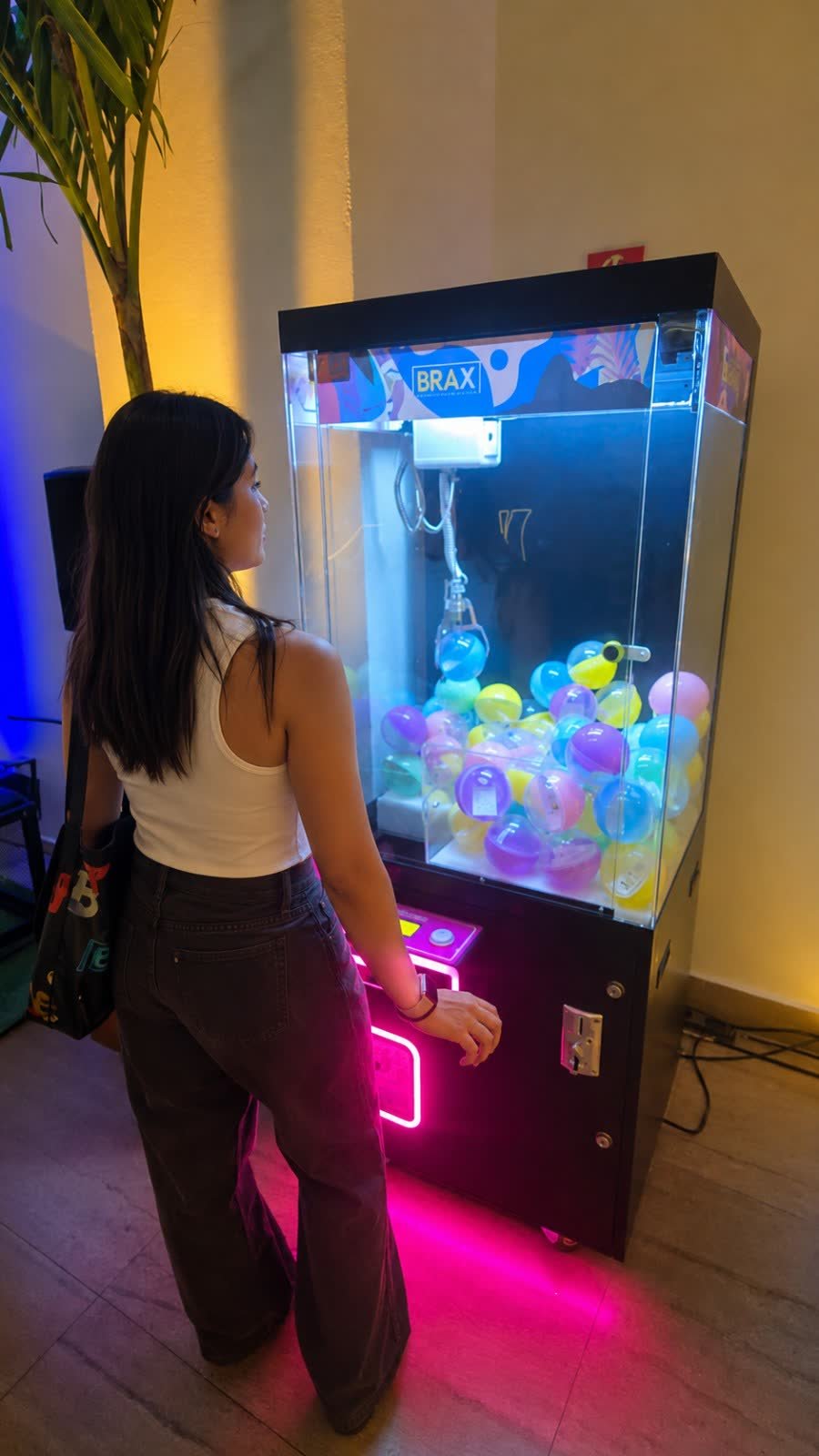 Participante se aproximando da máquina de garra personalizada com a identidade da marca