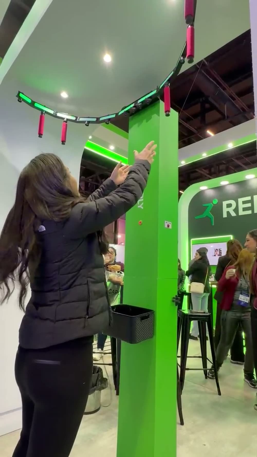 Participante com os dois braços erguidos tentando pegar um bastão que solta do arco de LED durante o evento